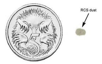 This image shows a round coin with a much smaller indistinct grey shape next to it, for size comparison, with an arrow and the words “RCS dust” labelling the grey shape.