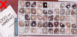 This image shows a tray divided into multiple compartments, each with a lump of mineral. There is a booklet in the background with the words “Rocks and minerals” printed on it.